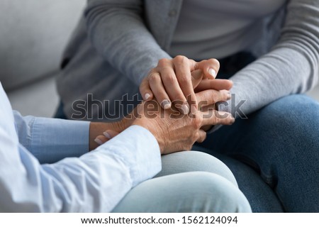 Young woman granddaughter daughter hold old female hand of mother grandma sit on sofa, two women generation help support concept, senior people parents grandparents care and comfort, close up view