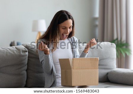Woman sit on couch screaming with joy opens carton box feel happy, addressee girl received long-awaited package, fast easy and quick post mail parcel delivery, reliable postal courier service concept
