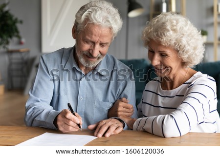 60s elderly spouses at lawyer office sitting at desk hoary husband holding pen family ready sign marriage contract make legal formalities at notary, bequeath savings and property to children concept