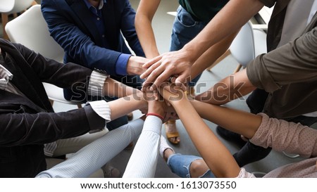 Top close up lot of hands stacked together as symbol concept of teambuilding, loyalty, amity and warm relations between office workers seminar participants, business success celebration, start of work