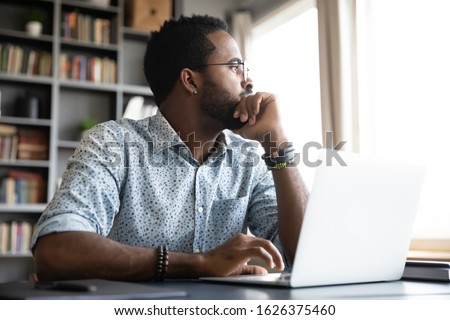 Thoughtful serious african professional business man sit with laptop thinking of difficult project challenge looking for problem solution searching creative ideas lost in thoughts at home office desk Foto stock © 