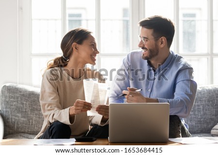 Couple sit on sofa busy with manage household budget, satisfied wife and husband using pc free online app for tracking spend of money, family individual entrepreneurs own business makes profit concept