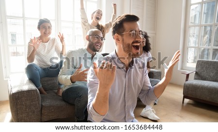 Excited multicultural friends soccer fans gathered together in sunny living room at home watching on tv sportive game feels euphoric waiting for goal, hobby, tournament viewers, sport betting concept Photo stock © 