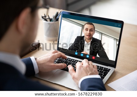 Pc screen view over businessman shoulder, due to corona virus all communications, business negotiations, perform distantly via videoconference, to exclude risk of infection outbreak and spread concept