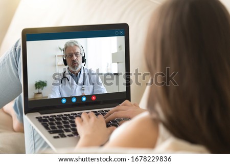 Pc monitor view over girl shoulder, old doctor wear uniform headset give consultation to client via internet about epidemic outbreak of corona virus ncov, distant communication and protection concept