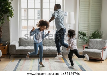 Active african funny dad little son and crazy daughter heavy metal or rock and roll lovers dancing in cozy living room relish life fooling around listening cool music scream with joy enjoy party hard