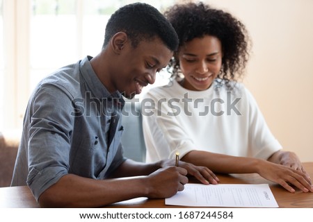 Satisfied African ethnicity couple affirming prenuptial contract, smiling husband putting signature on lease agreement, young family taking loan in bank filling form, health insurance buyers concept ストックフォト © 