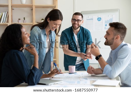 Smiling diverse colleagues gather in boardroom brainstorm discuss financial statistics together, happy multiracial coworkers have fun cooperating working together at office meeting, teamwork concept Stock foto © 