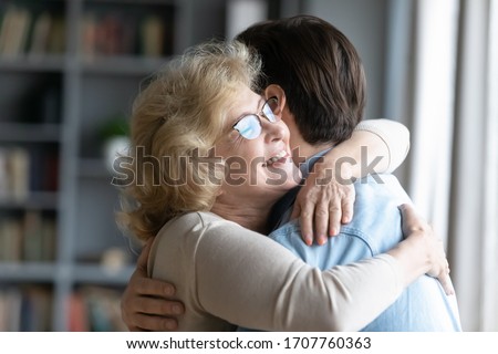 Loving elderly mother in glasses closed eyes enjoy moment strong cuddles adult son after long separation, grandmother glad to see grandson multi generational family reunion, love and bonding concept