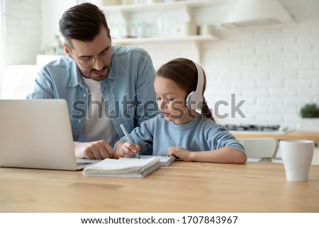 Caring young father help little preschooler daughter studying together watch online lesson on laptop, attentive dad and small girl child learn at home, have web class on computer on quarantine