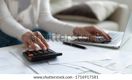 Close up of woman busy paying bills online on computer calculating household finances or taxes on machine, female manage home family expenditures, using calculator, make payment on laptop Foto d'archivio © 