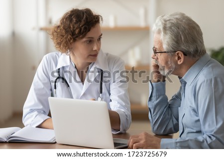 Young female professional doctor physician consulting old male patient, talking to senior adult man client at medical checkup visit. Geriatric diseases treatment. Elderly medical health care concept