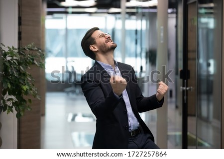 Millennial office worker in suit standing in hallway clenched fists feel overjoyed celebrate career advancement, got business opportunity, salary or sales growth, successful winner businessman concept 商業照片 © 