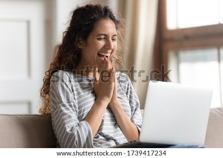 Excited woman looking at laptop screen, rejoicing good news, happy laughing girl reading email or message in social network, win online lottery, great shopping offer, sitting on cozy sofa at home
