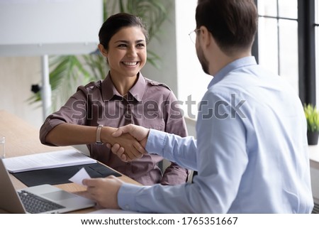 Recruiter shaking successful smiling Indian businesswoman candidate hand at meeting, congratulating with getting new job, manager making great deal with customer, diverse business partners greeting