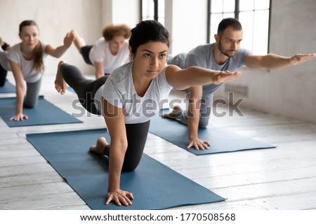 Similar – Image, Stock Photo Group of calm focused women and men practicing yoga with trainer standing in balance pose and stretching body in studio