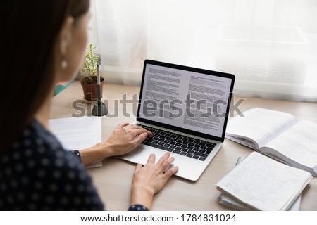 Back view close up of female student sit at desk at home look at laptop screen typing, focused millennial woman student busy studying distant on computer, browse document on gadget, education concept