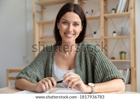 Head shot close up portrait smiling businesswoman talking, looking at camera, sitting at desk in office, confident friendly business coach mentor recording video, manager consulting client online 商業照片 © 
