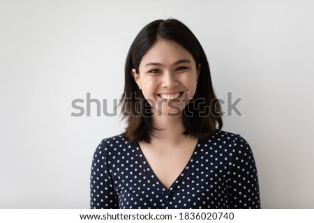 Profile picture of smiling millennial asian girl isolated on grey wall background look at camera posing. Headshot portrait of happy young Vietnamese woman renter or tenant satisfied with service.