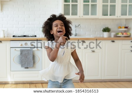 Similar – Image, Stock Photo Little girl singing holding headphones cord imitating herself a real singer. Child having fun jumping dancing listening to music on bed in bedroom at home