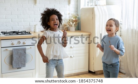 Similar – Image, Stock Photo Little girl singing holding headphones cord imitating herself a real singer. Child having fun jumping dancing listening to music on bed in bedroom at home