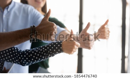 We all say yes! Close up shot of four young people workers clients of different gender ethnicity raising thumbs up showing general support acceptance recognition to company policy, service or product