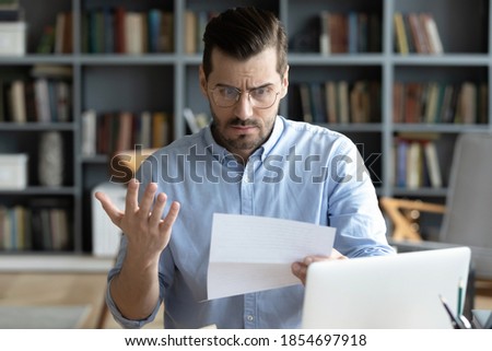 Man sit at desk in home office receive correspondence holding paper complaint letter read negative information awful news feels stressed about bank debt, high taxes to pay, financial problems concept