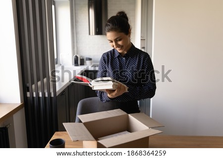 Happy millennial female of indian ethnicity preparing moving relocation to new home packing things. Glad proud young hindu woman author get parcel with personal copies of book from publishing house Сток-фото © 
