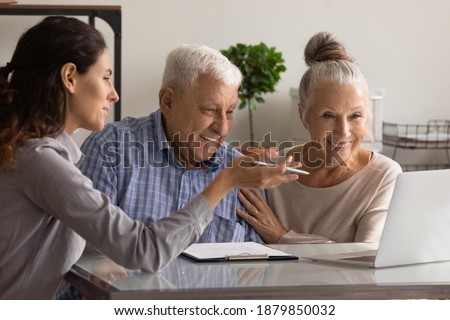 Female banking specialist consult happy mature couple about loan or mortgage at meeting in office. Woman consultant advise recommend elderly spouses good medical life health insurance on computer.