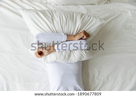 Top view depressed woman covering face with pillow, lying on bed at home alone, frustrated unhappy young female suffering from insomnia, mental or relationship problems, break up or divorce Stock foto © 