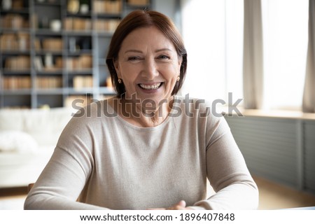 Head shot portrait smiling mature woman making video call, grandmother chatting with relatives, using webcam, happy middle aged blogger recording vlog, teacher holding online lesson, distance lecture