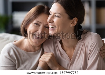 Close up head shot portrait smiling mature mother and grownup daughter cuddling, family enjoying tender moment, happy young woman with elderly mum hugging, spending leisure time together