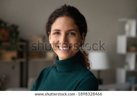 Close up portrait of smiling young Caucasian woman look at camera feel excited optimistic. Happy millennial 20s female renter or tenant overjoyed moving relocating to new home or apartment.