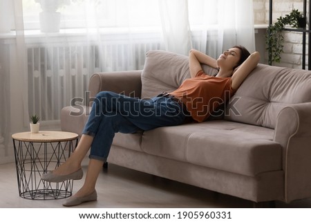 Peaceful young woman relaxing on comfortable couch at home, calm tranquil attractive female taking nap, resting with closed eyes on cozy sofa in modern living room, leaning back, daydreaming ストックフォト © 