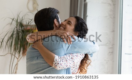 In your warm embraces. Excited wife holding beloved husband tight in arms grateful for support love care. Young couple hug reconciling after family fight or missing each other spending long time apart