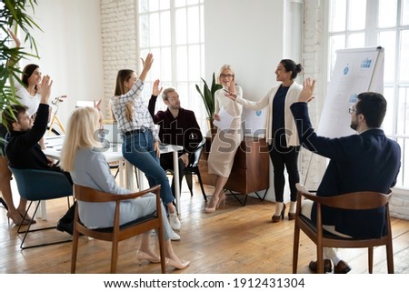 Motivated employees raising hands, asking coach at training. Presenter finishing workshop with questions from engaged audience. Indian female business leader interacting with team at corporate meeting