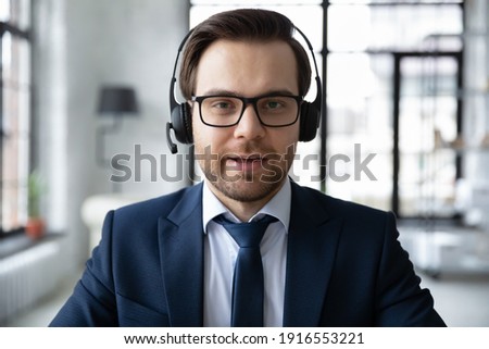 Close up headshot portrait of male CEO or director in headphones talk speak on video call in office with business client. Caucasian businessman wear earphones have webcam digital virtual conference.