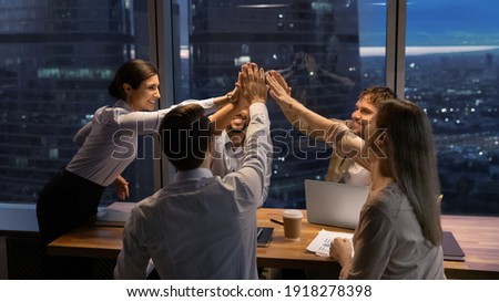 Motivated multinational team raise high fives on briefing after finding problem solution as successful brainstorm result. Happy workers unite hands above conference desk celebrate common achievement Photo stock © 