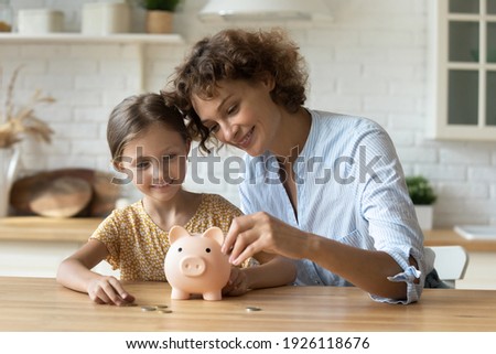 Setting good example. Young parent mother teach child little daughter girl to manage finances save money spend earnings with economy plan family budget. Friendly mom and kid thrift coins in piggybank