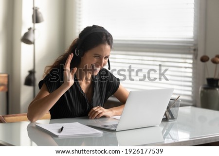 Overjoyed woman wearing headphones waving hand, looking at laptop screen, chatting online, making video call, teacher or businesswoman greeting viewers, involved in conference, virtual meeting Photo stock © 