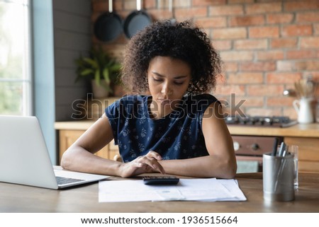 Serious mixed race female calculate utility charges check payments sum by loan contract to avoid scam. Thoughtful young black woman engaged in planning monthly budget count tax rate before pay online Foto d'archivio © 