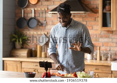 Cooking master class. Confident black man vlogger shoot tutorial teach audience to make healthy food. Young african guy capable cook broadcast live preparing national cuisine dish on domestic kitchen