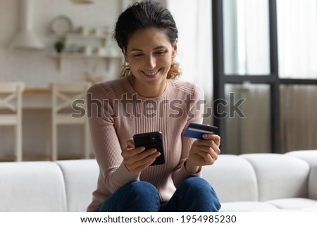 Safe mobile banking. Smiling latina lady client hold mobile phone credit bank card do online shopping provide internet payment. Happy young woman enjoy easy fast secure transferring money in ebank app