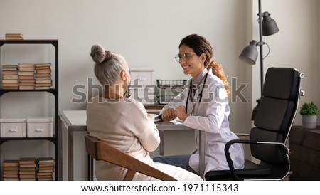 You are doing well. Happy latin woman medic glad to inform senior female patient about positive treatment dynamics. Optimistic doc encourage elderly lady visitor tell good news about her health status Photo stock © 