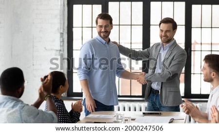 Proud boss encouraging and thanking happy employee for good job, shaking hand. Excited worker getting promotion, recognition, respect and applause of colleagues. Leader introducing new team member