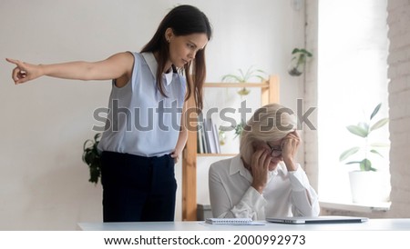 Angry young Caucasian female boss or CEO ask middle-aged employee leave office. Mad confident businesswoman fire unhappy senior woman worker, dissatisfied with work results. Dismissal concept. Foto d'archivio © 