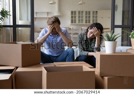 Exhausted young couple sit rest on sofa in living room near heap of cardboard boxes feel unmotivated to unpack their belongings. Financial problem, debt and eviction, hard long relocation day concept Photo stock © 