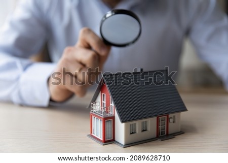 Man appraiser hold magnifying glass examining cottage house miniature, bank officer using zoom checking assessment of dwelling. Concept of real estate appraisal, property, land valuation, house search Stockfoto © 