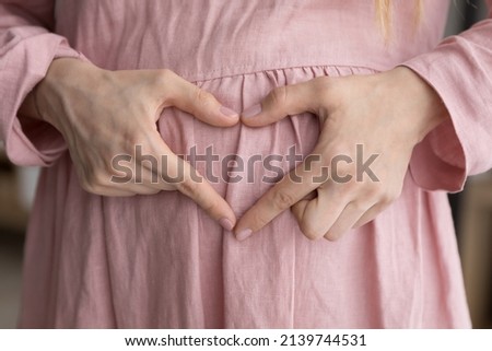 Close up happy young woman making heart sign gesture with fingers on pregnant belly, feeling inspired waiting for first baby, showing unconditional love and care to unborn child, expressing tenderness Imagine de stoc © 