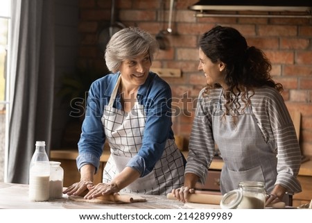 Happy Latin grown up daughter and senior mother cooking in home kitchen together, rolling dough for homemade pastry, bakery food, talking, laughing, enjoying leisure time, common hobby together Stok fotoğraf © 